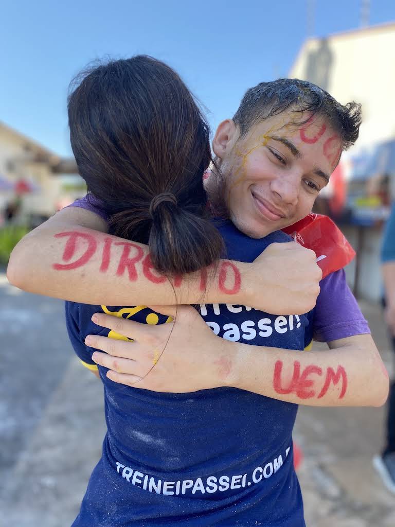 Abraço entre dois aprovados, com Direito e UEM pintados nos braços.
