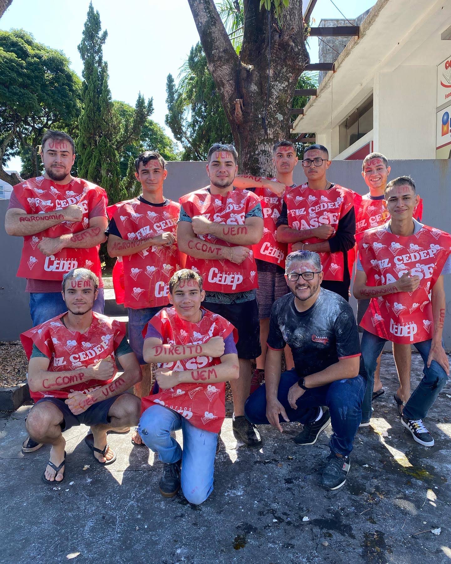 Grupo de alunos aprovados posando com a capa do CEDEP e os cursos escritos nos braços.