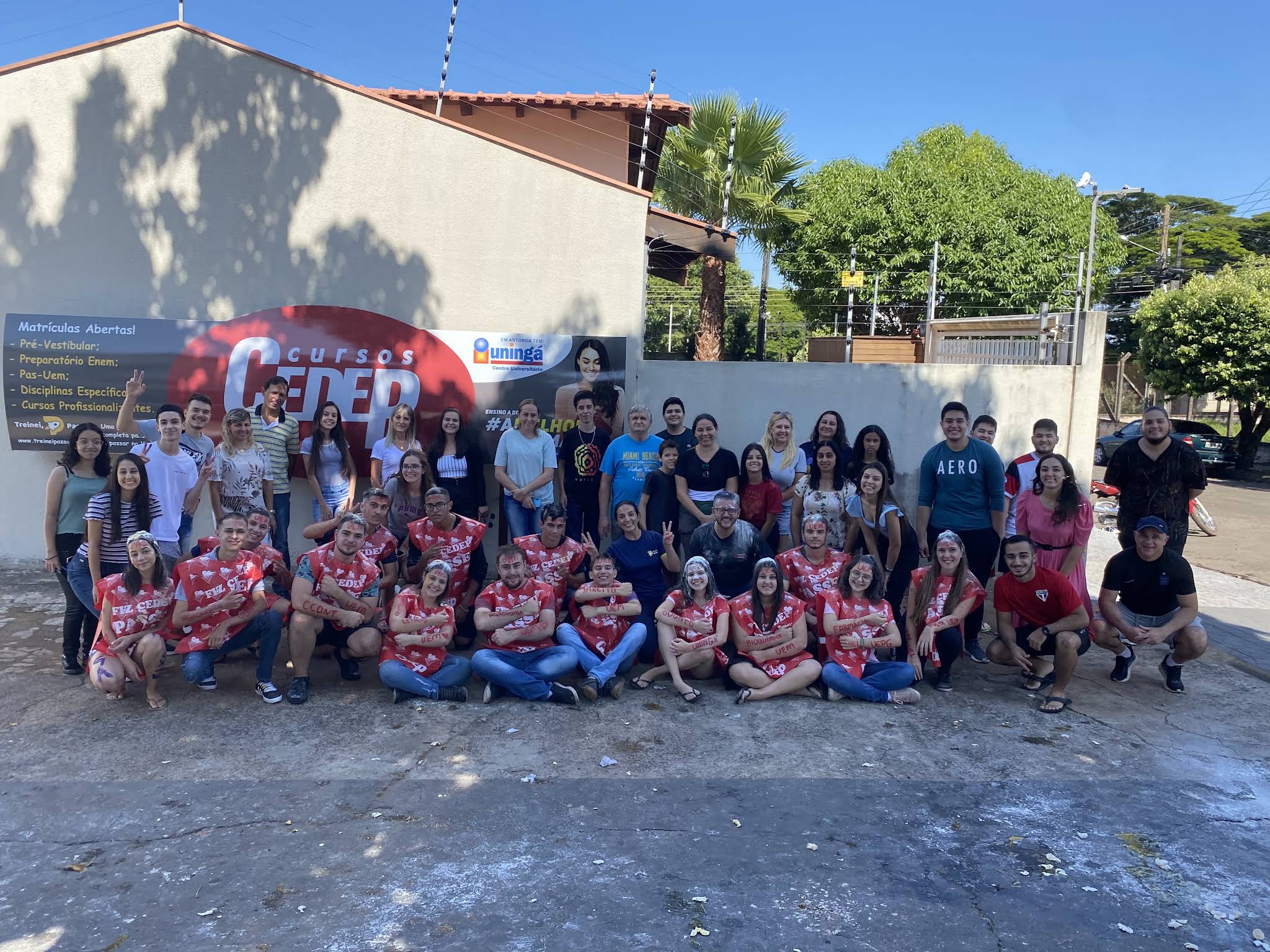 Turma de aprovados reunida em frente à escola, todos com a capa vermelha do CEDEP.